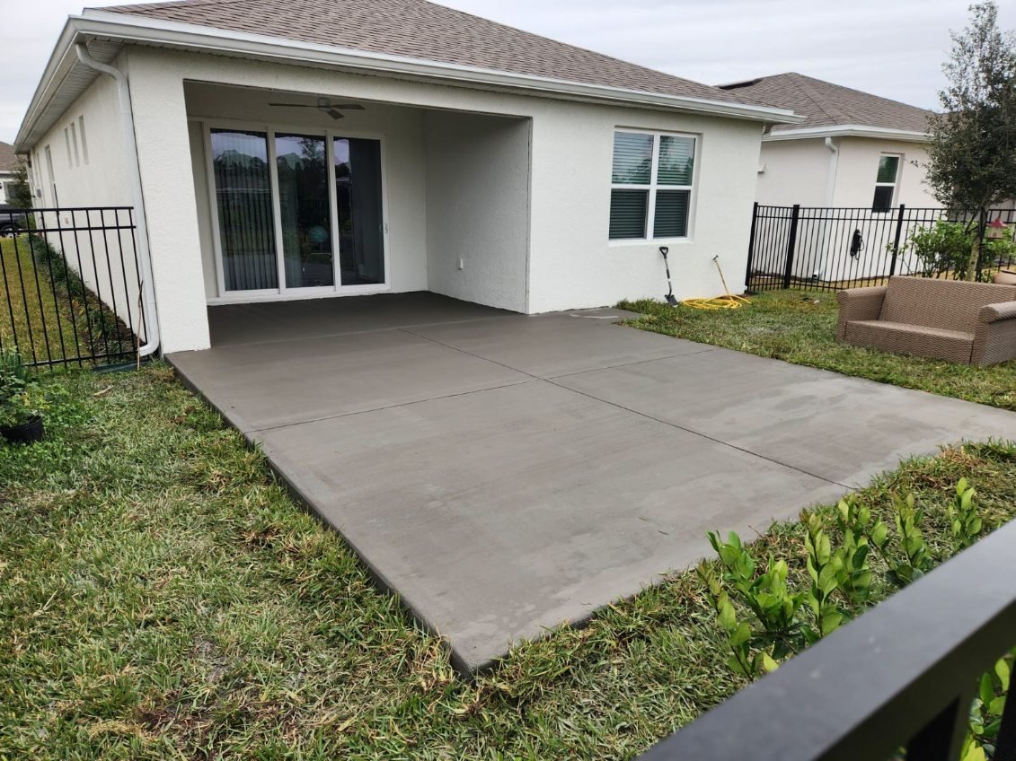 New dark concrete patio poured outside a covered porch