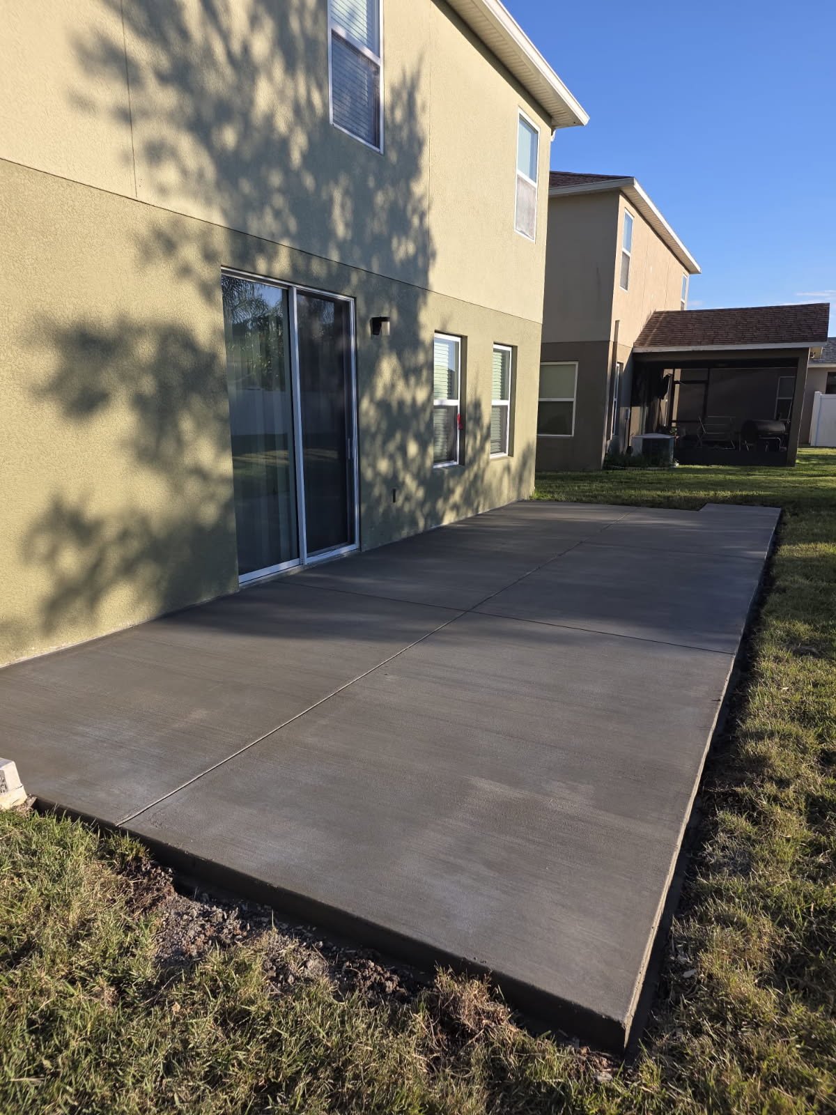 New concrete patio poured behind a two-story home