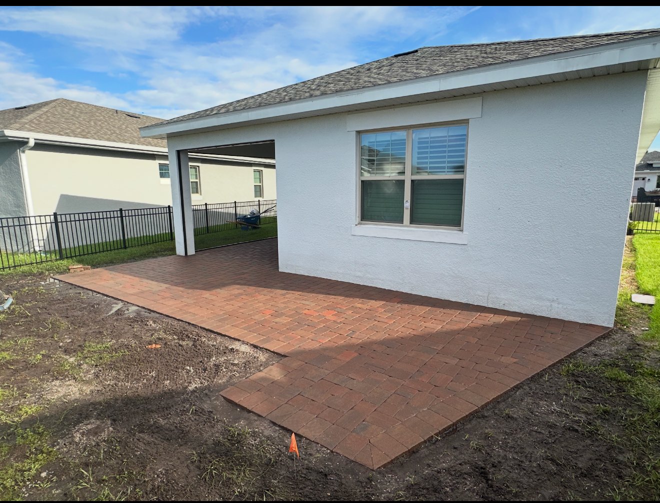 Red brick paver patio installed beside a white home