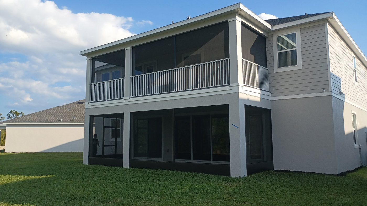 Two-story screened balcony and lanai enclosure on a gray home