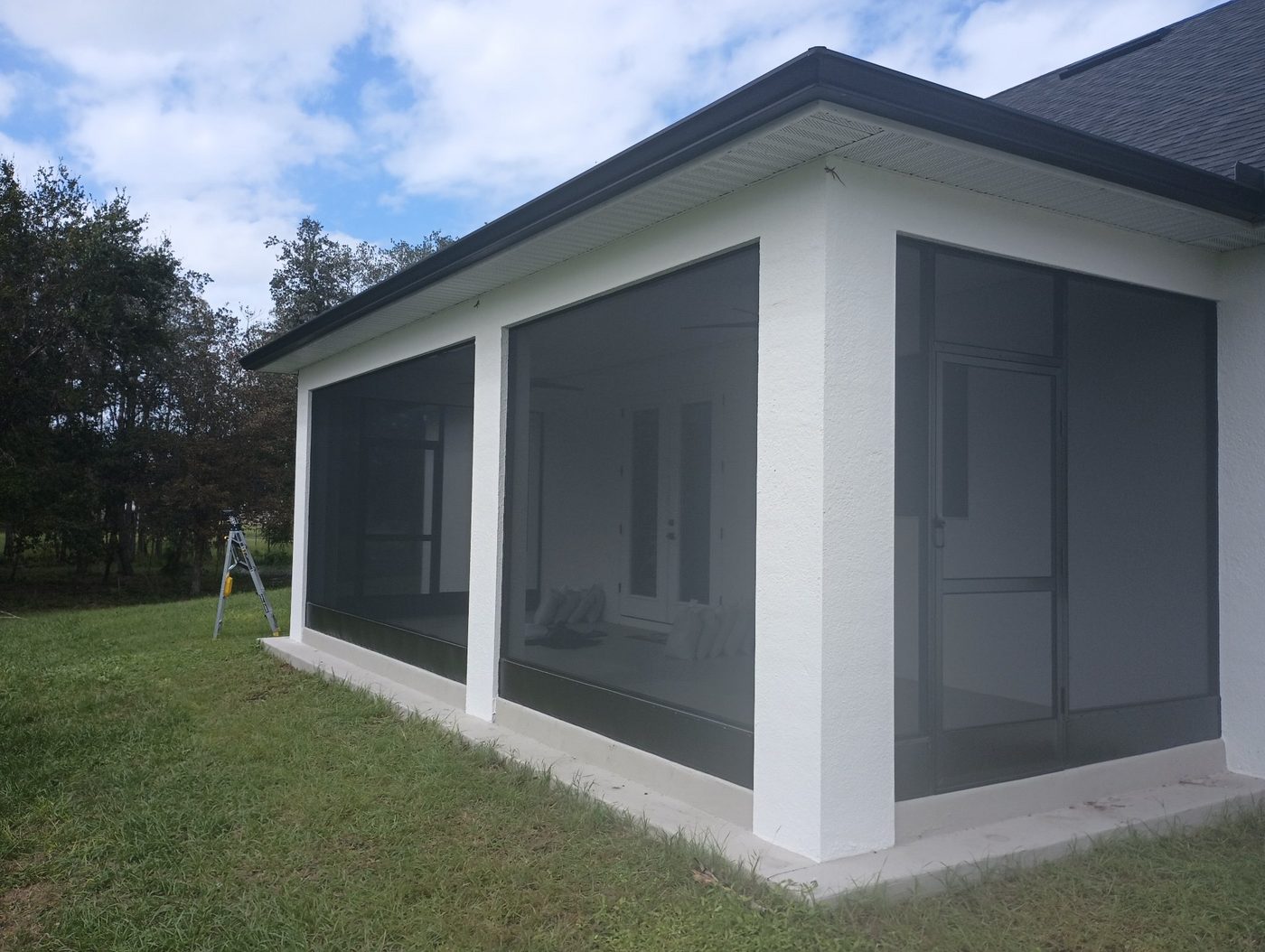 Large screened lanai with white framing and a dark insulated roof