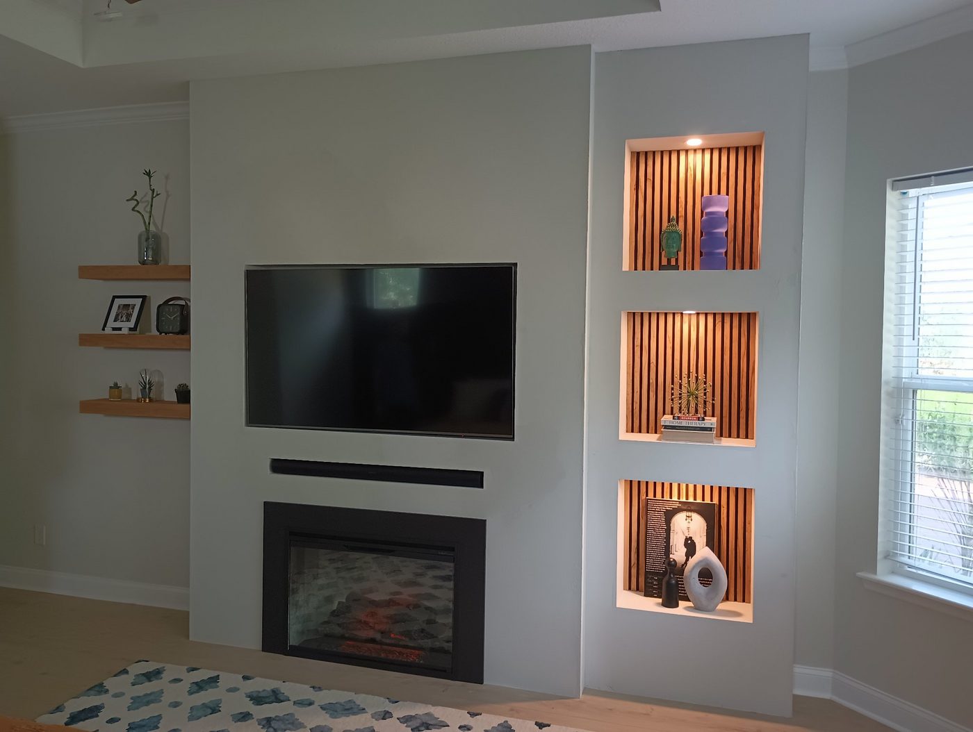 White fireplace wall with built-in niches and a mounted TV