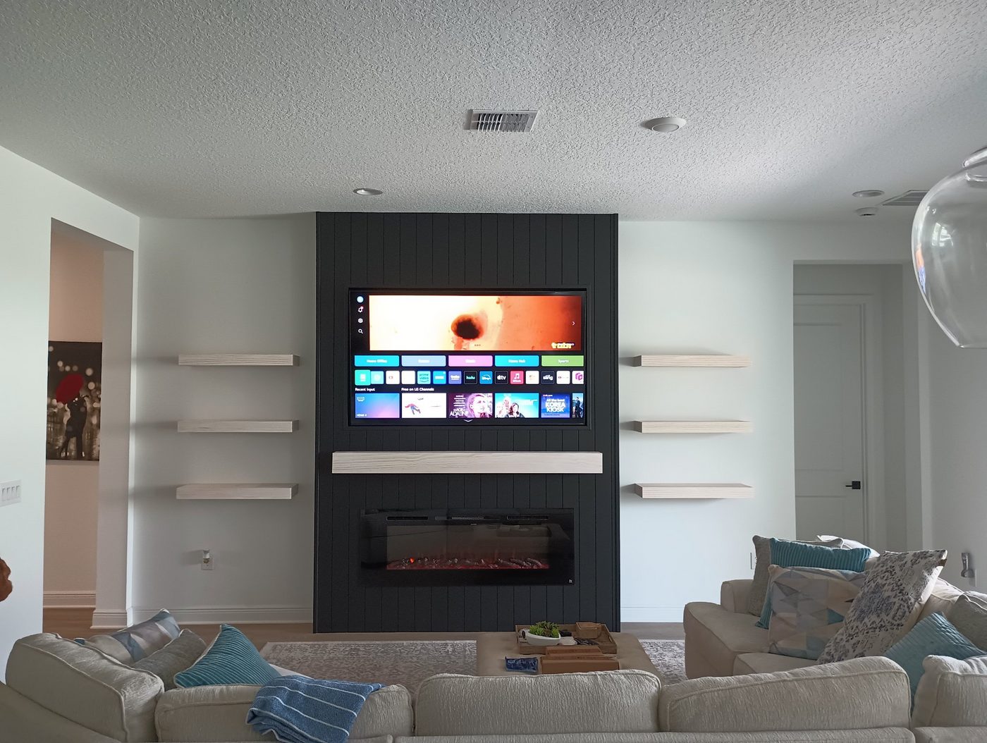 Dark fireplace wall with open shelves and a mounted TV