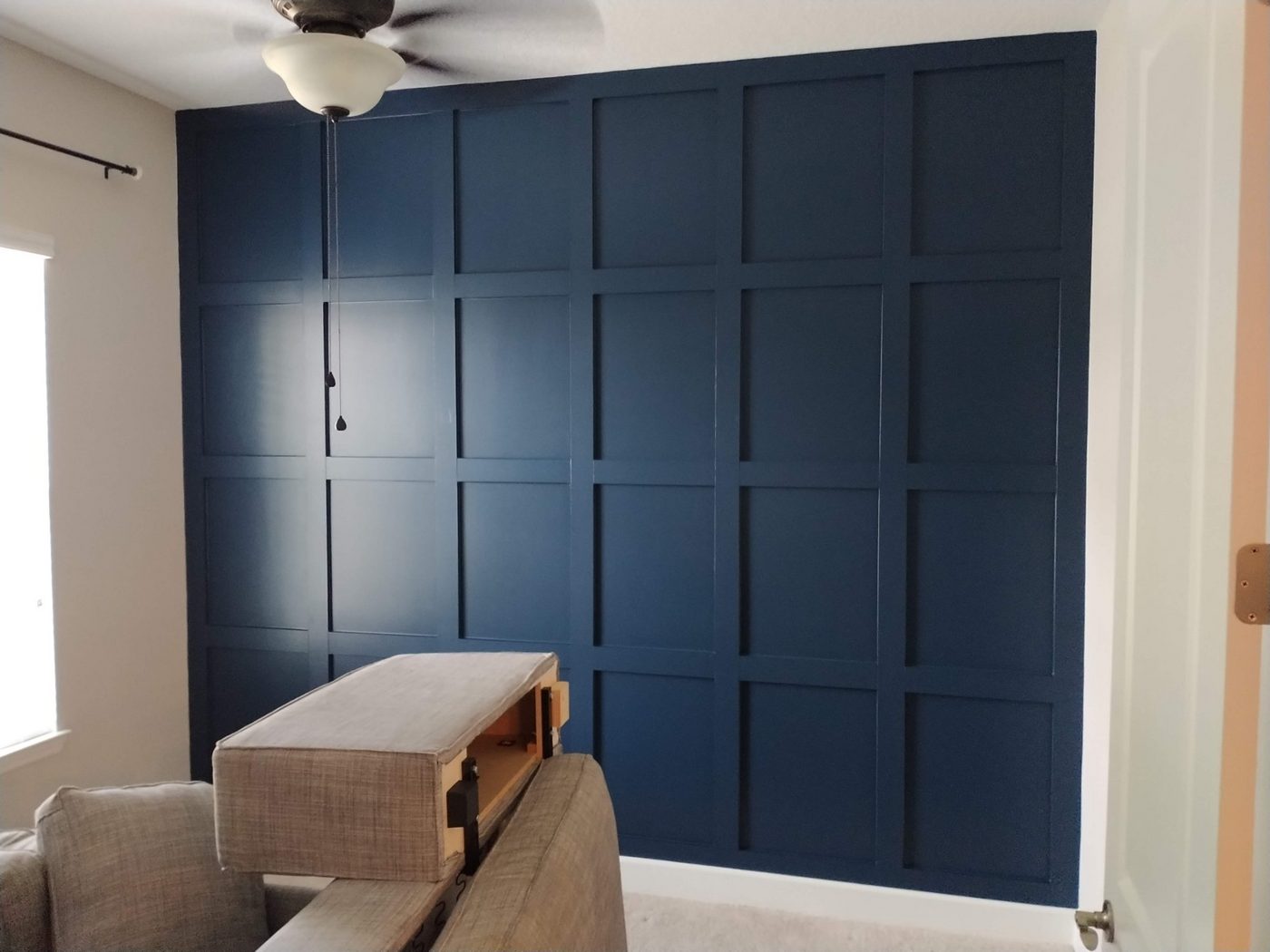 Navy shaker panel accent wall behind a TV
