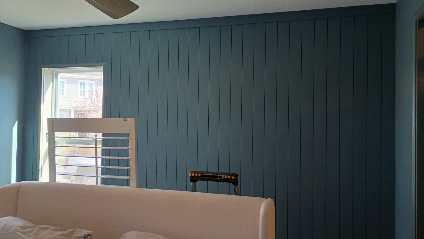 Blue vertical shiplap wall beside a window