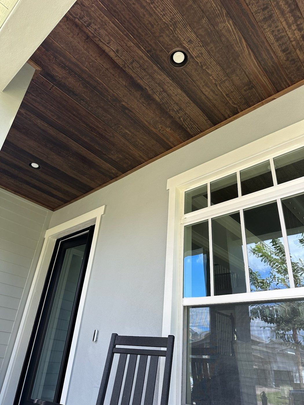 Porch with a wood plank ceiling, tall windows and trim columns