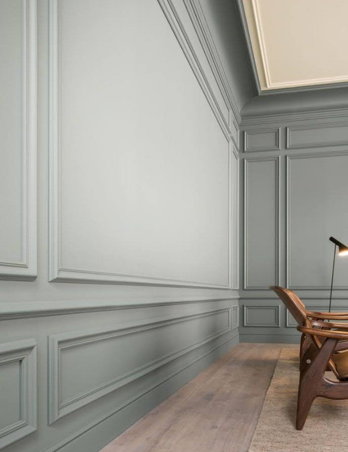 Gray paneled wall with crown molding and a wood chair
